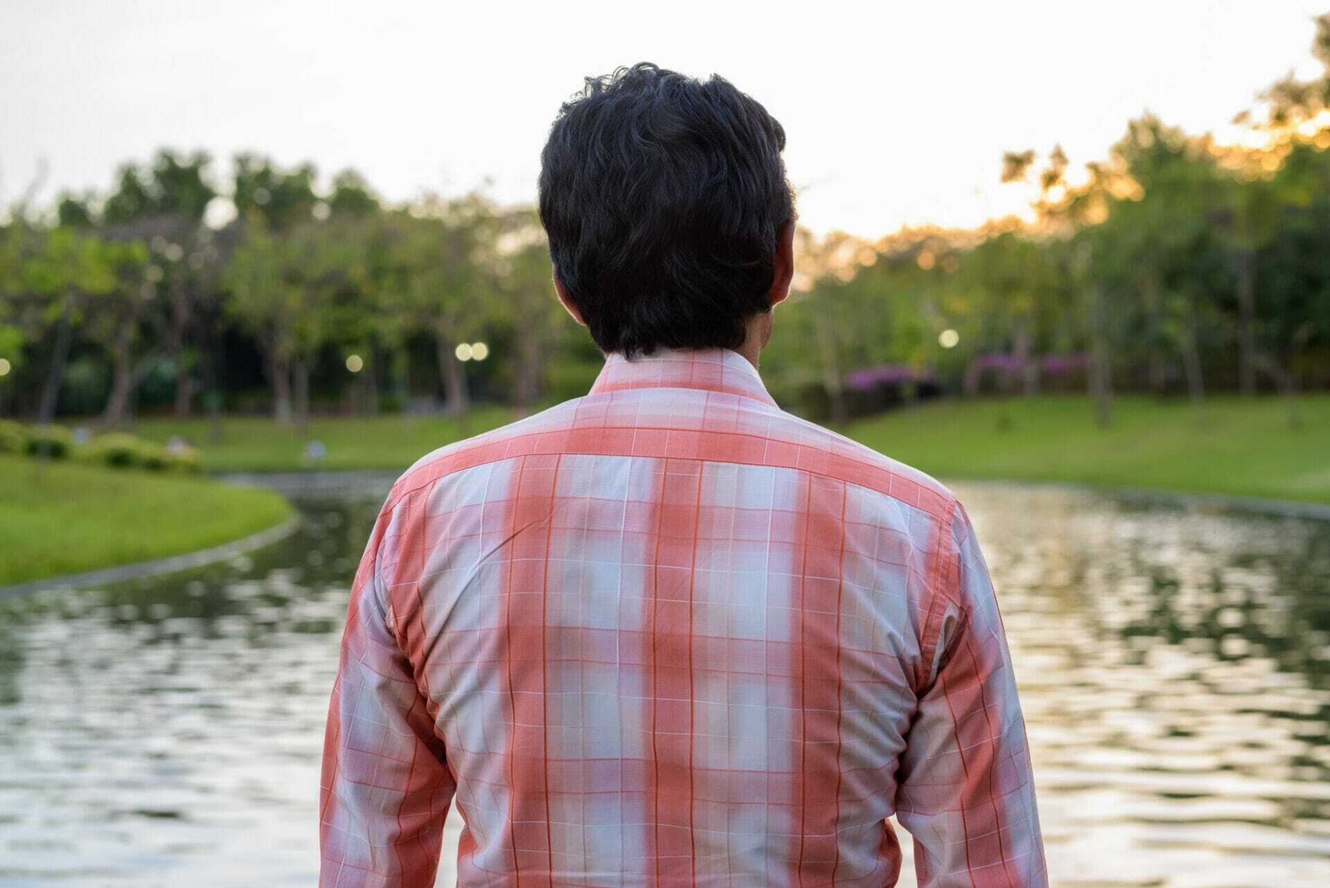 indian man looking at scenic view of the lake in peaceful green